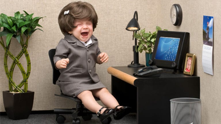 Crying baby in a salesperson's uniform and little cubicle