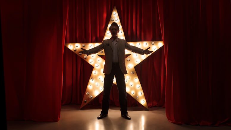 Man standing in front of a large lit up star on a stage
