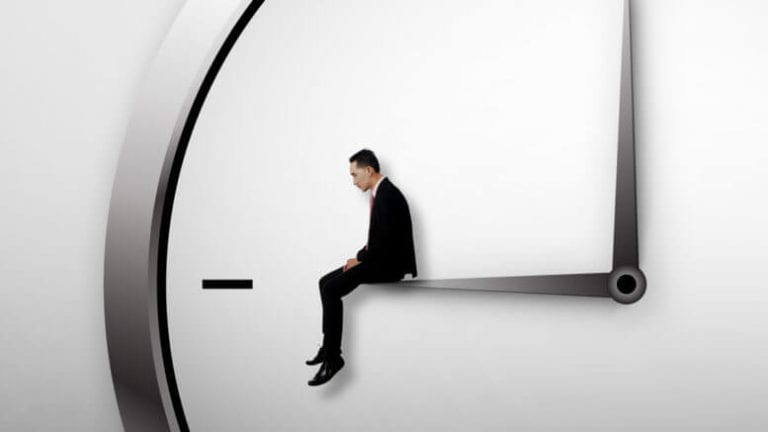 Small man in a suit sitting on a clock