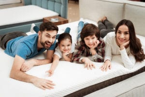 A family smiling and laying on a mattress
