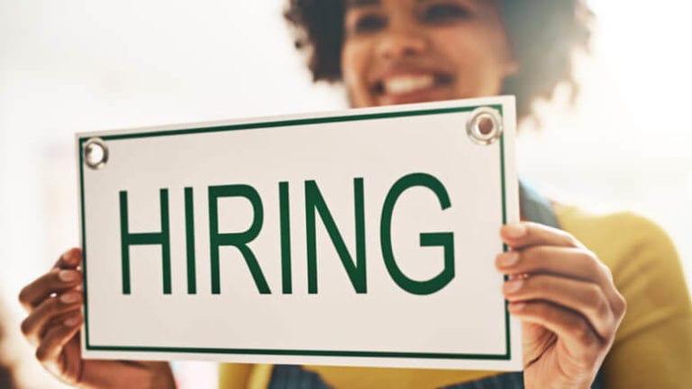 Woman holding a sign that says "hiring."