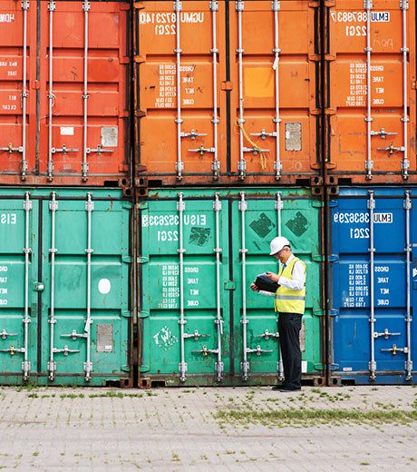 A workers stands in front of cargo containers