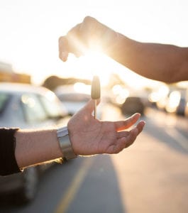 Person handing another person keys to a car