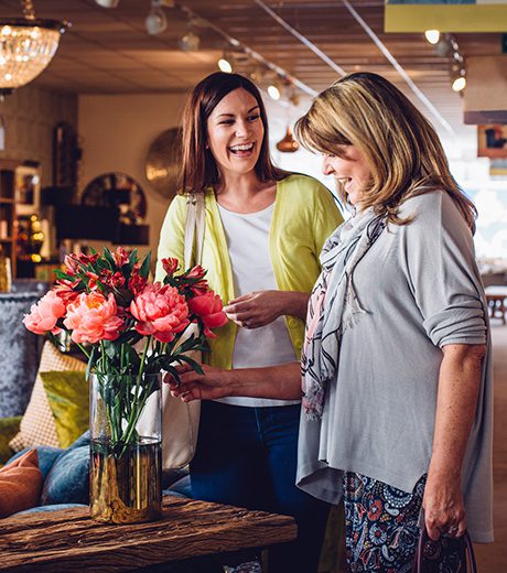 Woman helping another woman look for something in a furniture store