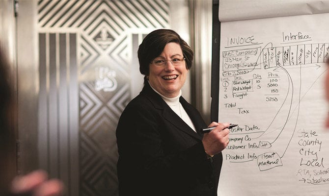 Photo shows a woman at a white board