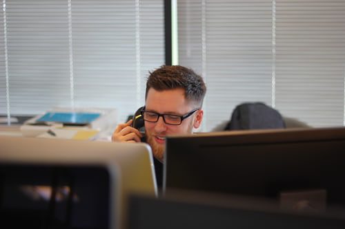 photo shows a man in an office making a phone call