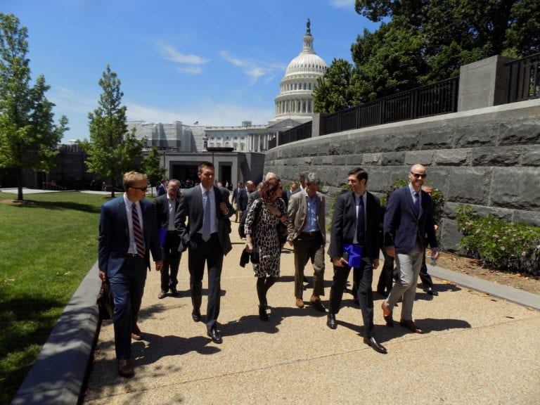 Photo shows a group of people walking with the U.S. Capitol in the background