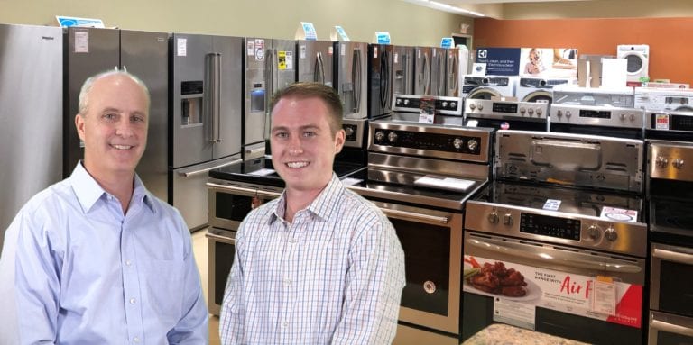 Image shows two men in the appliances section of their store