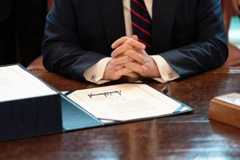 image shows the president's hands and a signed bill