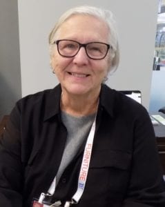 Image shows a woman with glasses and white hair
