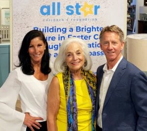 Image shows three people in from of a banner for the All Star Children's Foundation