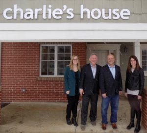 Image shows four people standing in front of Charlie's House
