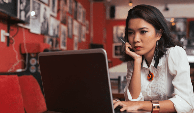 Image shows a woman looking intently at a laptop screen