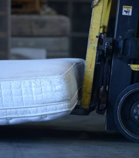 Image shows a forklift carrying a mattress