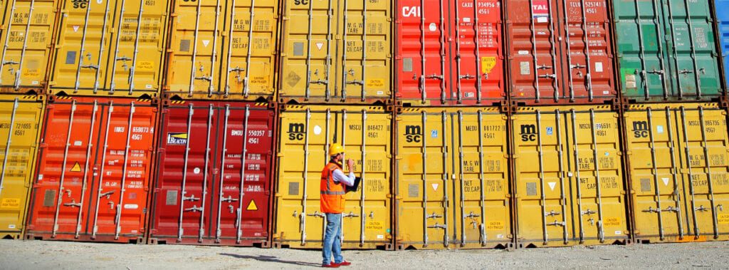 Man standing in front of a wall of cargo containers