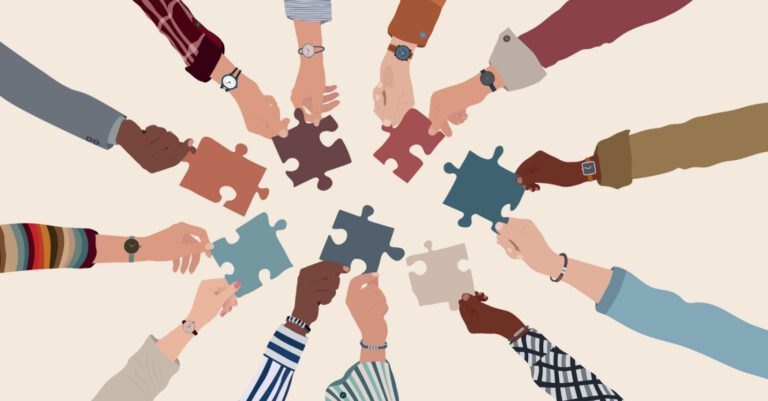 Multiracial hands holding puzzle pieces in a circle