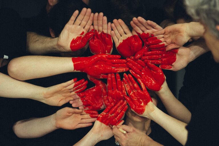 Multiple sets of hands all painted together to make a red heart