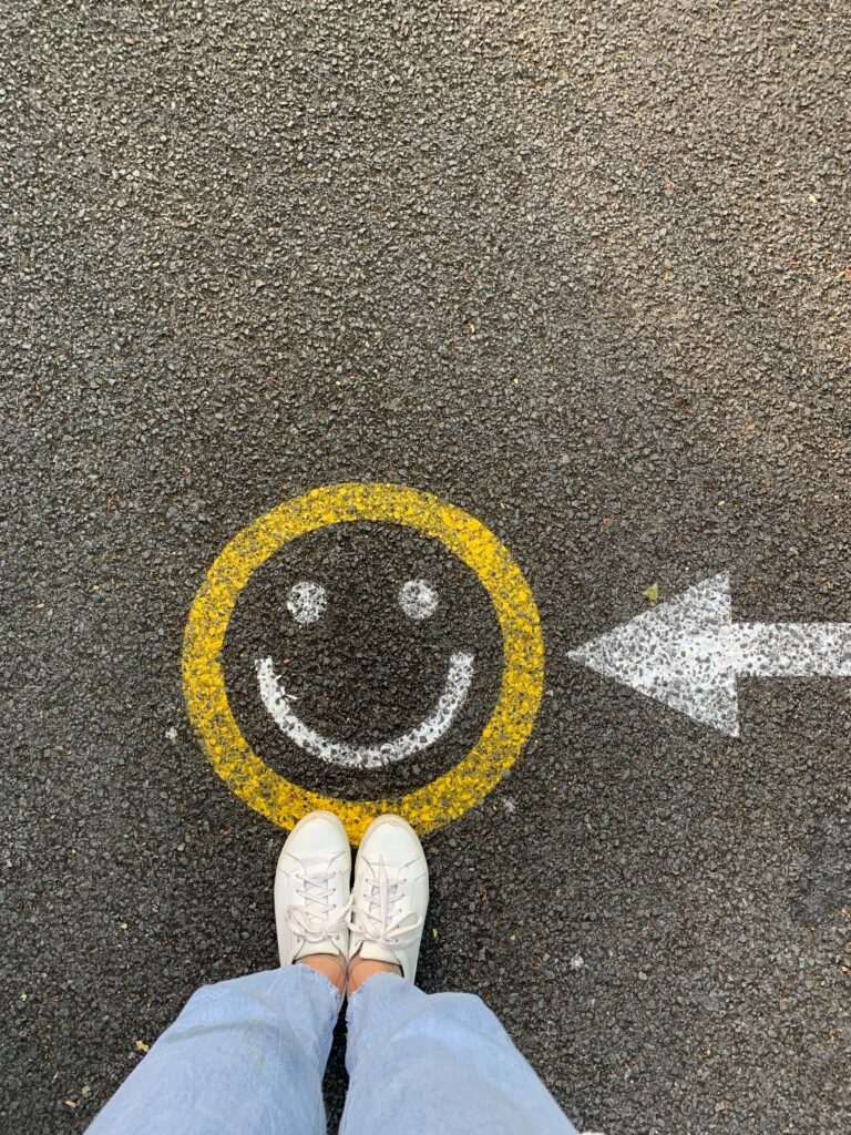 Happy face on ground with a person and arrow pointing to it