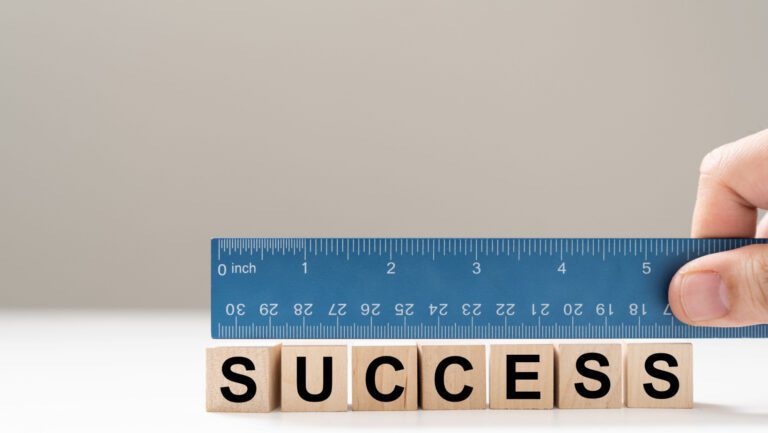 measure success with a blue ruler over tiles that spell out success