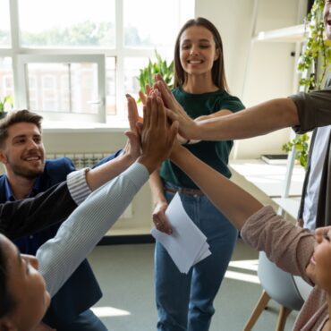 Happy motivated professional team celebrating success. Inspired office employees giving group high five, enjoying good teamwork result, work achievement, expressing teambuilding supportive spirit