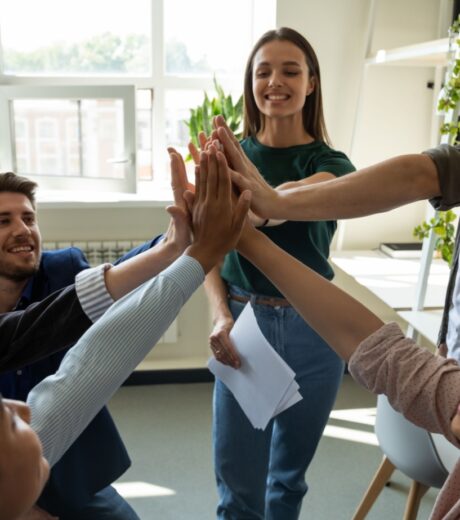 Happy motivated professional team celebrating success. Inspired office employees giving group high five, enjoying good teamwork result, work achievement, expressing teambuilding supportive spirit