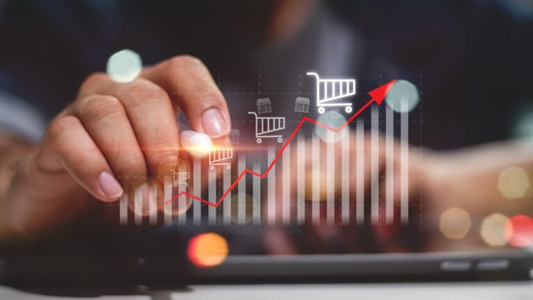 Sale growth concept. Businessman touching graph of increase in sales volume with shopping cart on virtual screen for ecommerce growth. Businessman pointing arrow graph corporate future growth plan