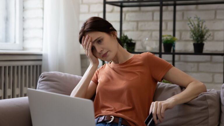 Unhappy young caucasian woman looking at computer screen, feeling frustrated with online shopping.