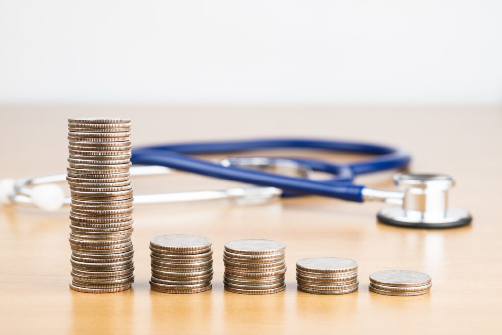 Stacked quarters showing cost savings on healthcare with stethoscope in background