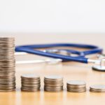 Stacked quarters showing cost savings on healthcare with stethoscope in background