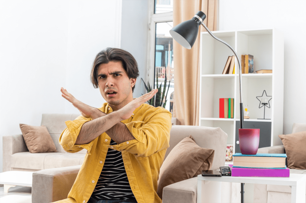Millennial man with his hands up in an "X" with an angry look on his face.