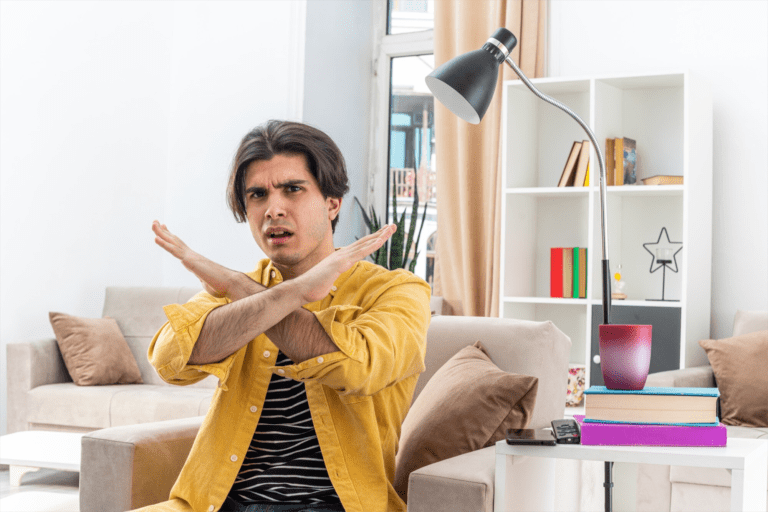 Millennial man with his hands up in an "X" with an angry look on his face.