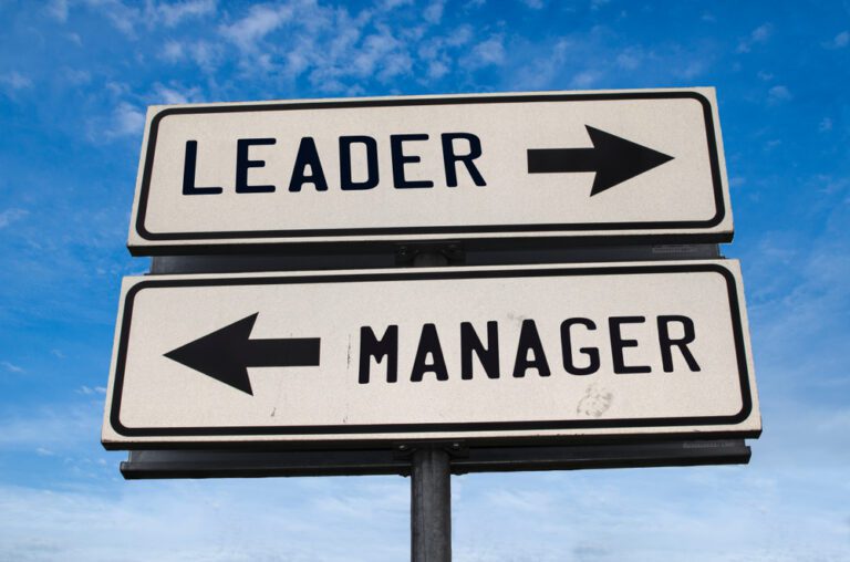 Leader vs manager. White two street signs with arrow on metal pole with word Leader and Manager. Directional road. Crossroads Road Sign, Two Arrow. Blue sky background.