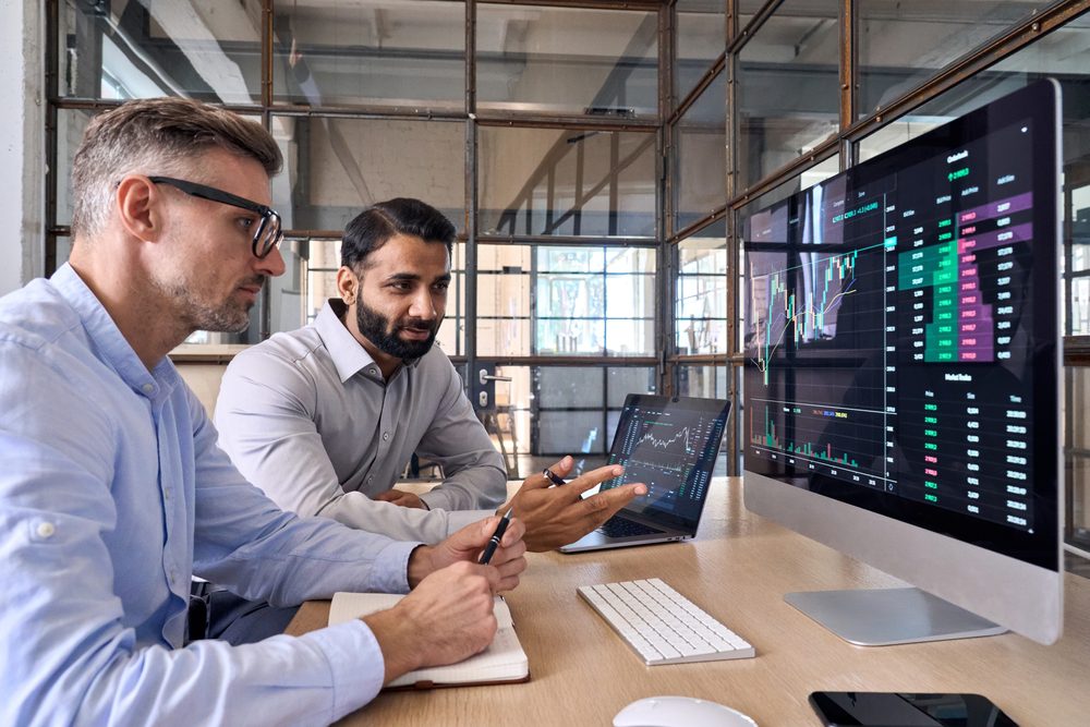 Two marketing managers discussing marketing POS data reports on a computer looking at screen