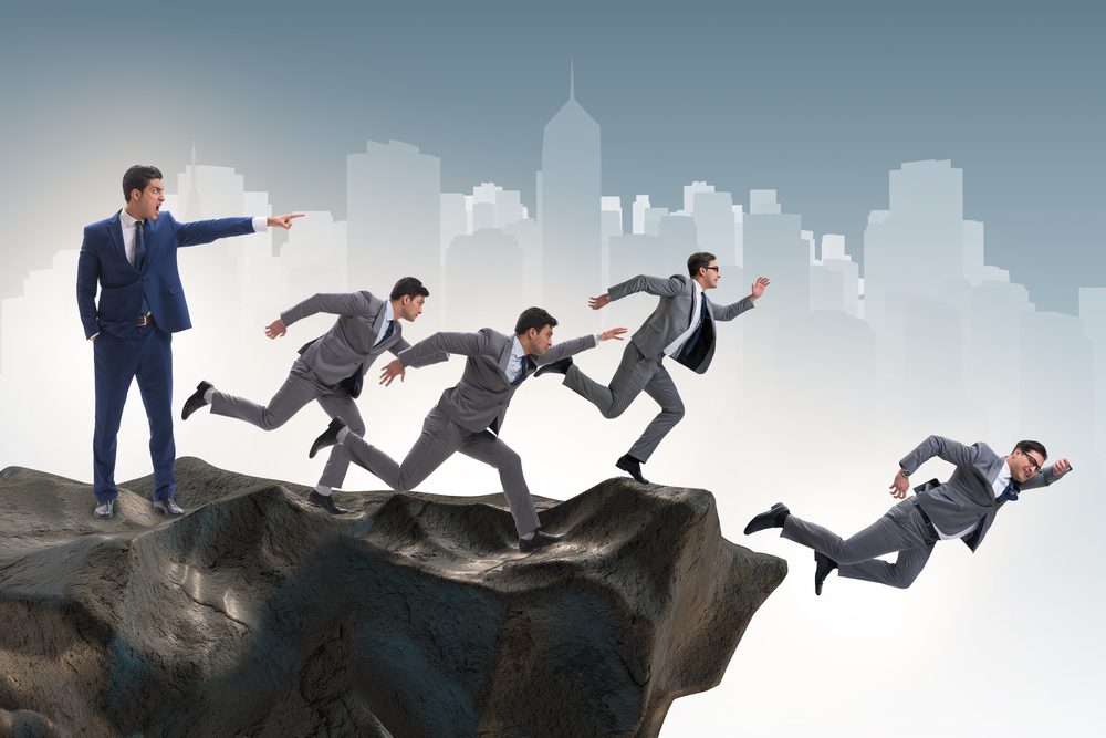 Businessman making poor decisions in business. Man shouting as other men are jumping off a cliff.