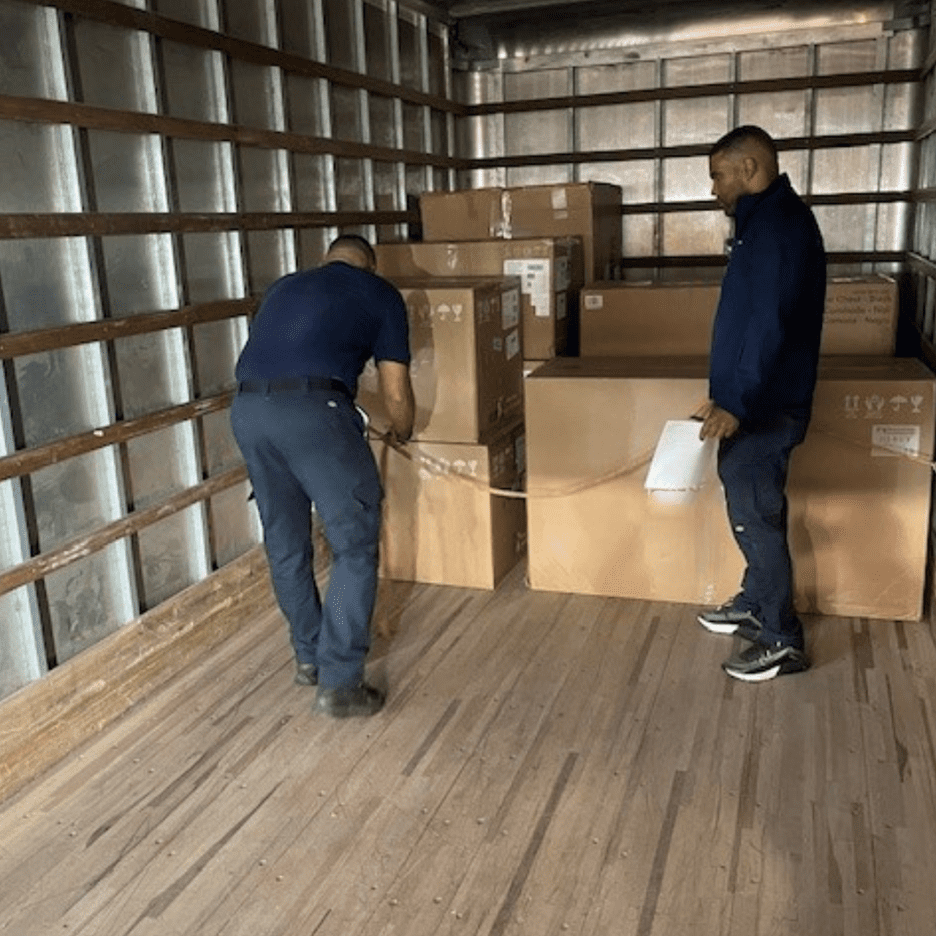 Two delivery men loading furniture into a truck for customer deliveries.