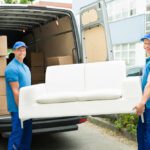 Two Happy Male Workers Putting Furniture And Boxes In Truck