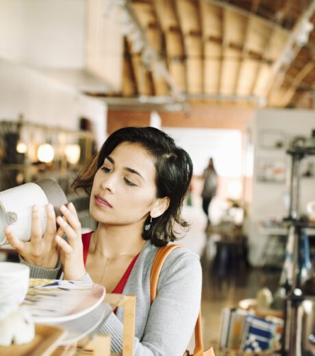 Young woman in a shop, looking at a ceramic jug