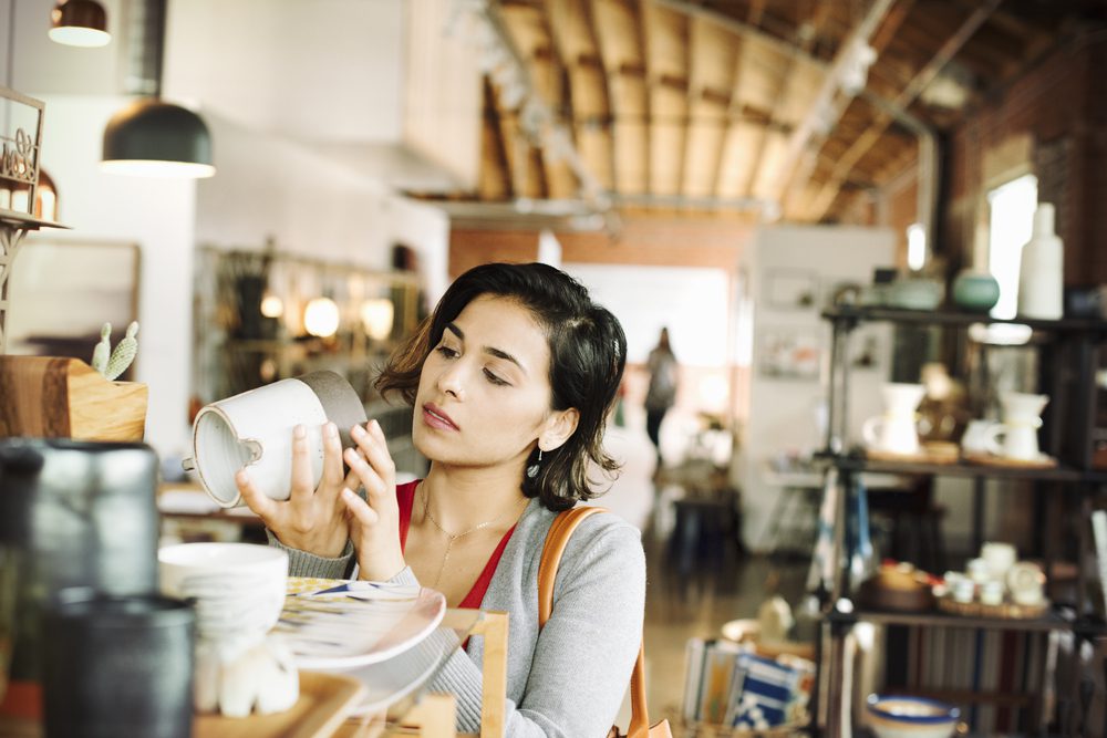 Young woman in a shop, looking at a ceramic jug