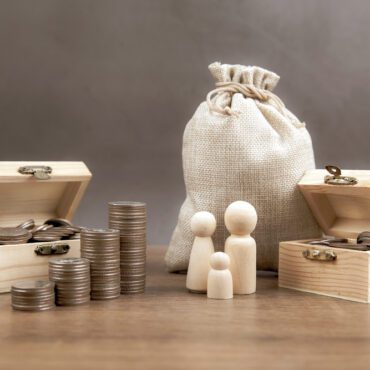 Many coins are stacked in a graph shape with family icons for money saving ideas and financial planning insurance.