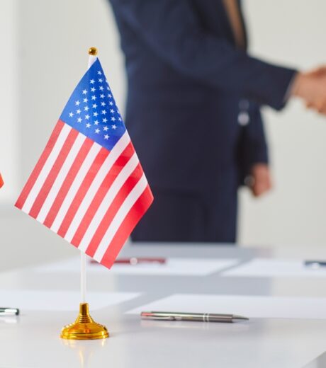Flags of China and America against background of handshakes of political representatives of these countries. Concept of bilateral political relations and cooperation between United States and China