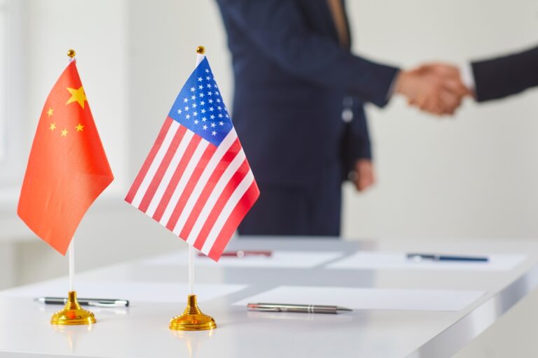 Flags of China and America against background of handshakes of political representatives of these countries. Concept of bilateral political relations and cooperation between United States and China