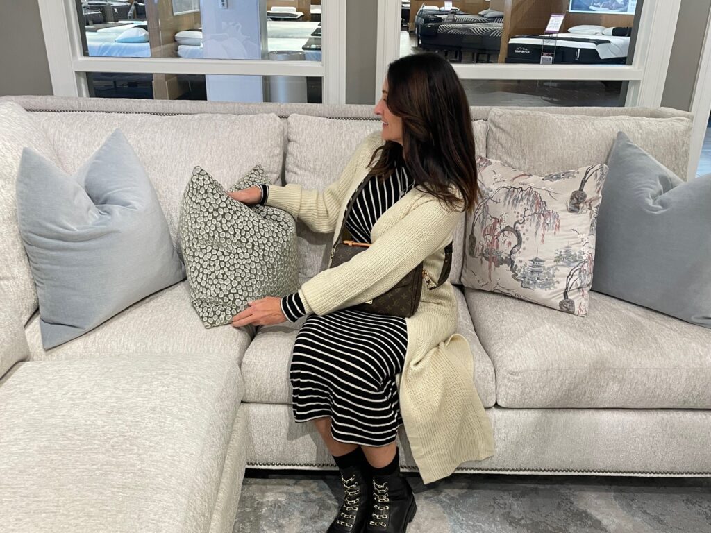Female shopper on sofa in furniture store fluffing pillow