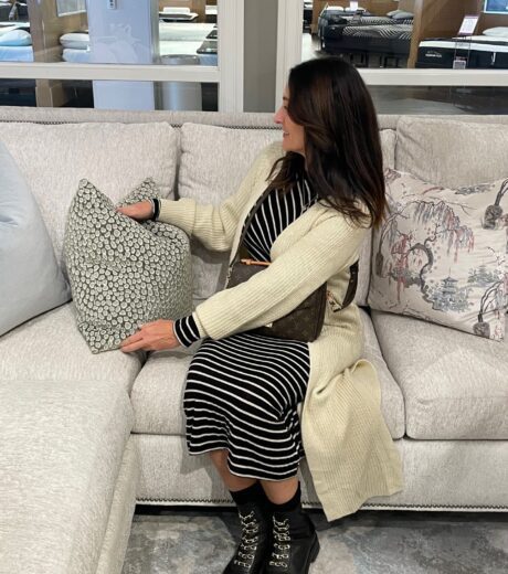 Female shopper on sofa in furniture store fluffing pillow