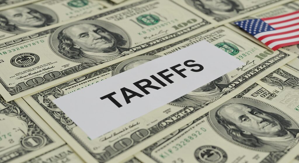 A symbolic image representing tariffs and their impact on the US economy, visualized by TARIFFS over hundreddollar bills and the American flag
