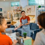 shop assistant man invites customers to see furniture products when customers arrive at the store