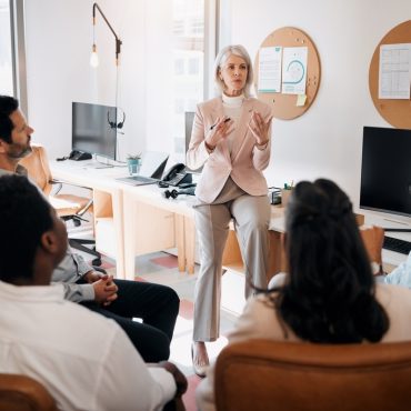 Business, mature manager or training team in office on risk management, financial planning or compliance. Finance department, diversity or people with upskilling to assess sales performance or budget