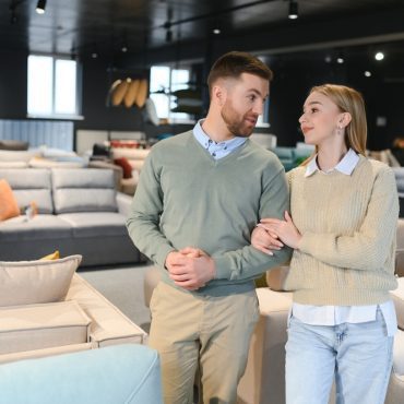 Couple choosing sofa and pillows at furniture store.