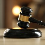 Judge's gavel on wooden table against blurred background, closeup