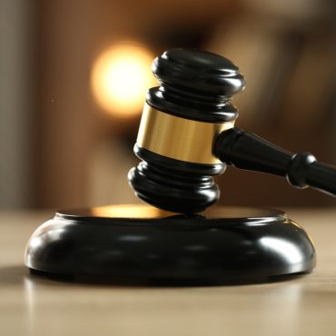 Judge's gavel on wooden table against blurred background, closeup