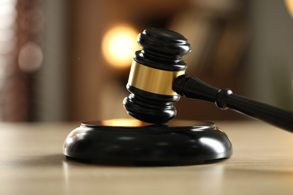 Judge's gavel on wooden table against blurred background, closeup